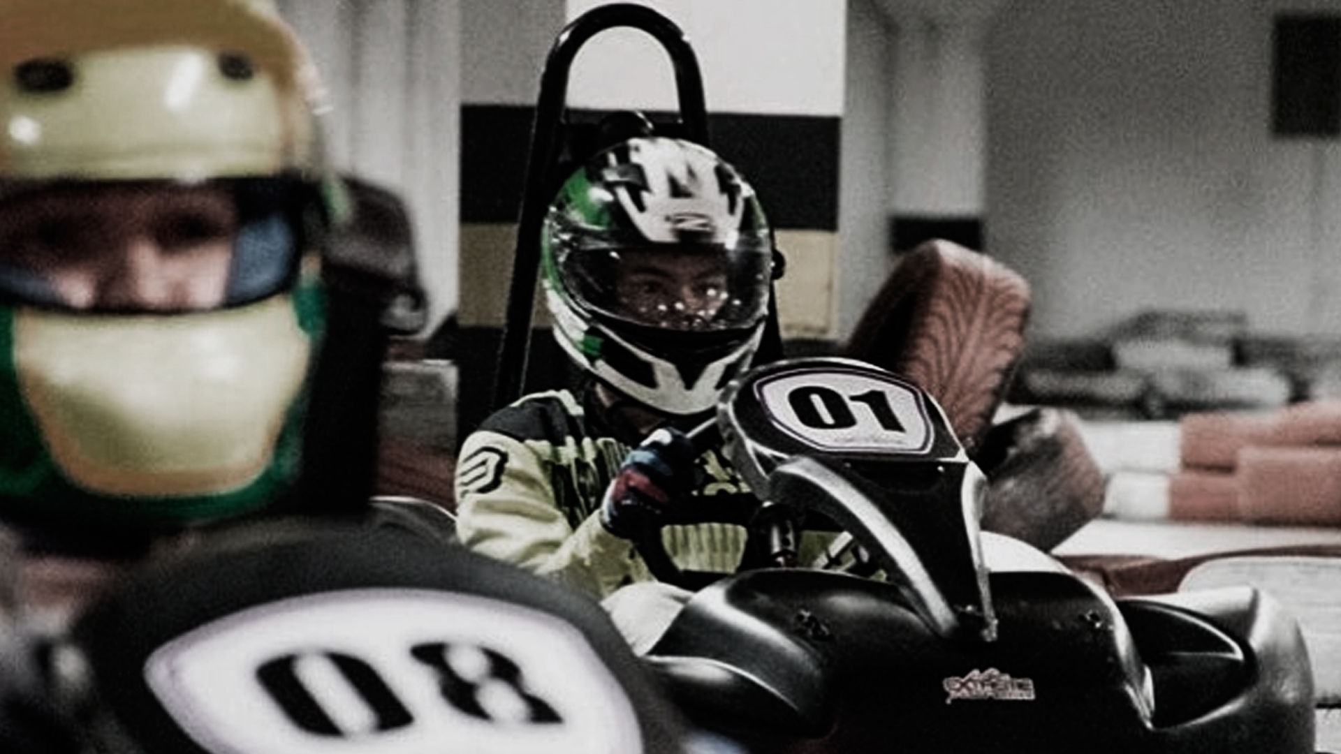 Dois pilotos de kart, preparados para iniciar a corrida no Kart Extra Curitiba, a maior pista de kart indoor de Curitiba