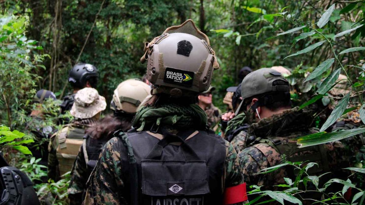 Na imagem há um time de airsoft, devidamente equipado, explorando um campo de airsoft ao ar livre.