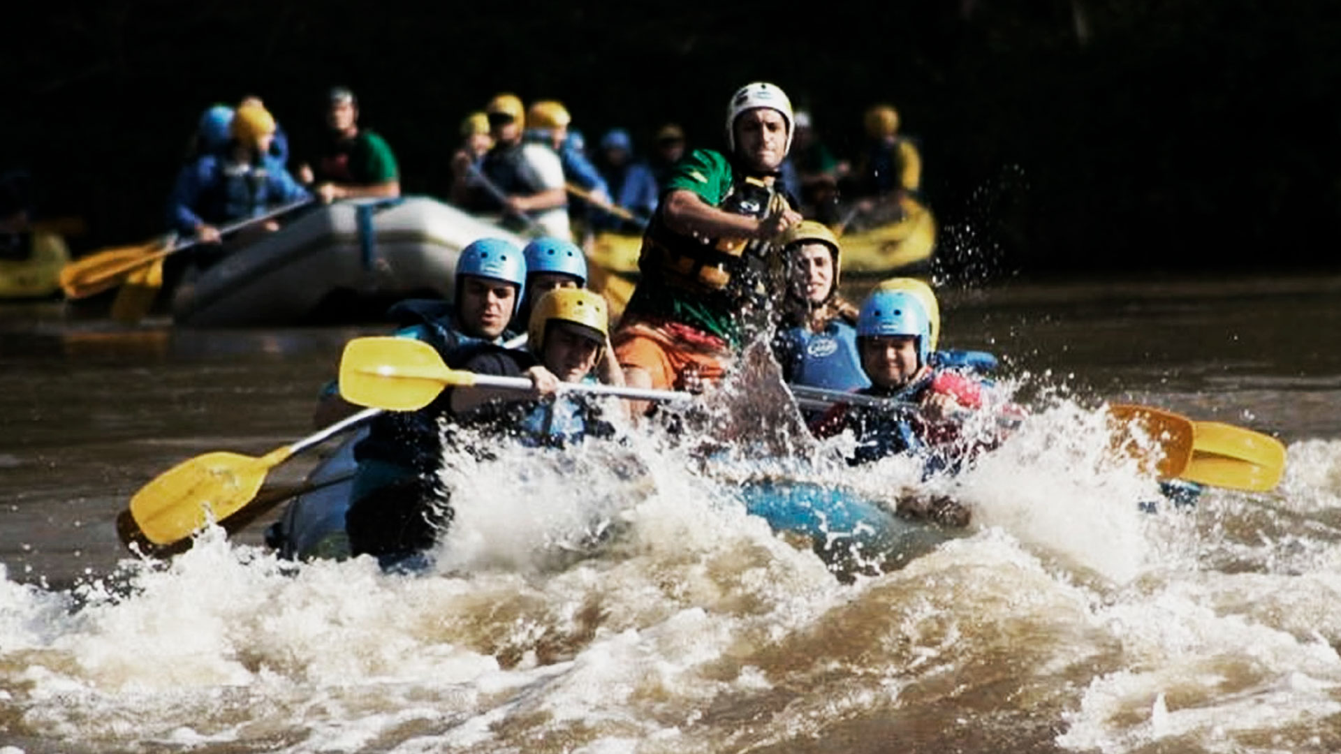 Grupo de pessoas em um bote azul praticando rafting no rio ribeira, em Cerro Azul.