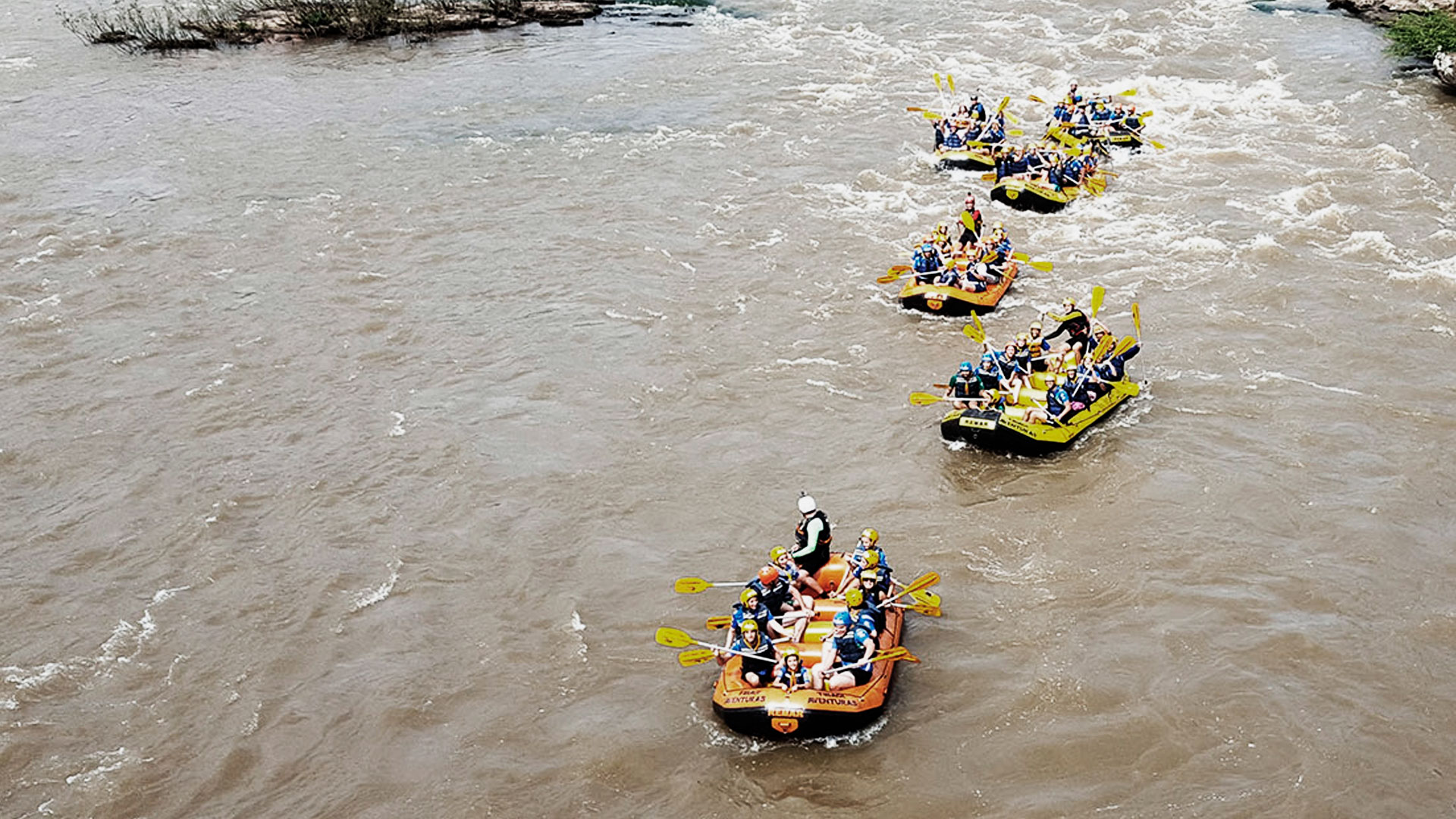 Grupo de pessoas em 6 botes praticando rafting no rio tibagi, em Tibagi.