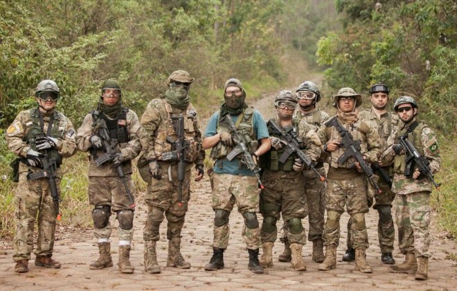 Na imagem, 9 jogadores de airsoft, vestindo os equipamentos para a prática pousam para a foto.