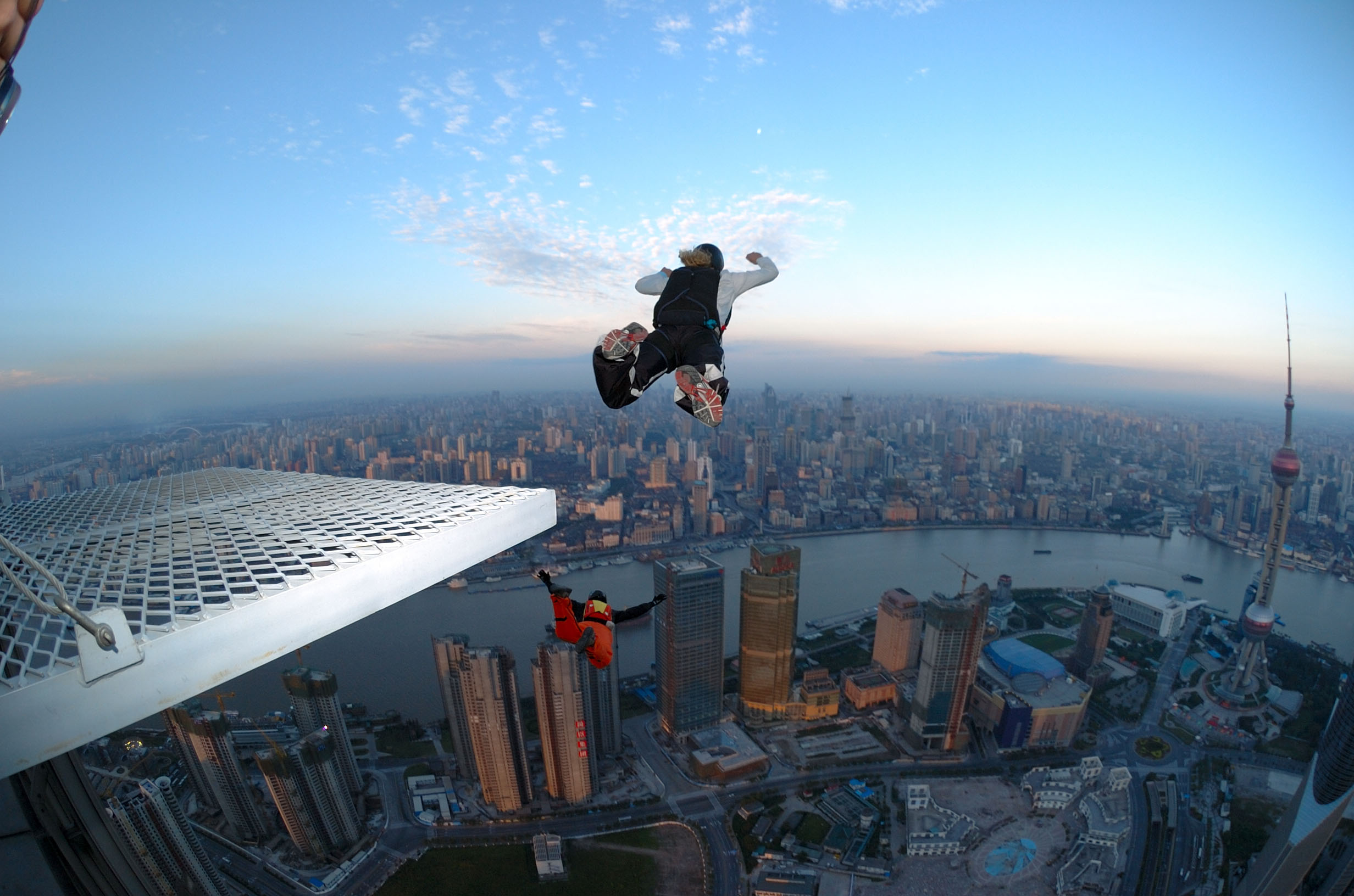 Na imagem, duas pessoas saltam de um pico em shanghai. 