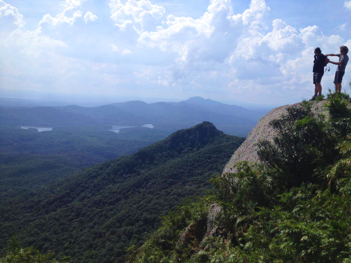 Na imagem, temos a vista do morro do canal. Duas pessoas estão no pico mais alto, e a vista é de outros morros secudários.