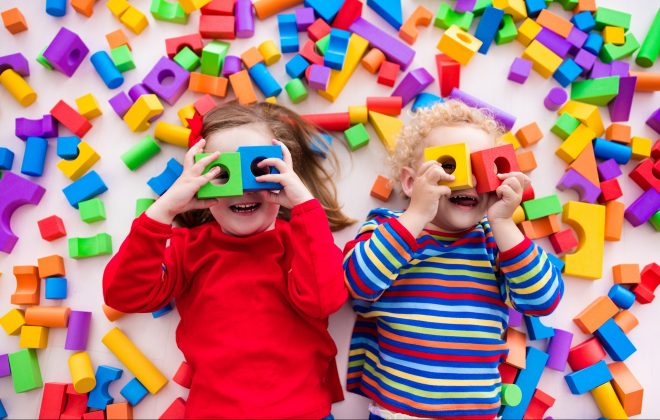 Duas crianças felizes brincam com blocos coloridos de construir brinquedos.