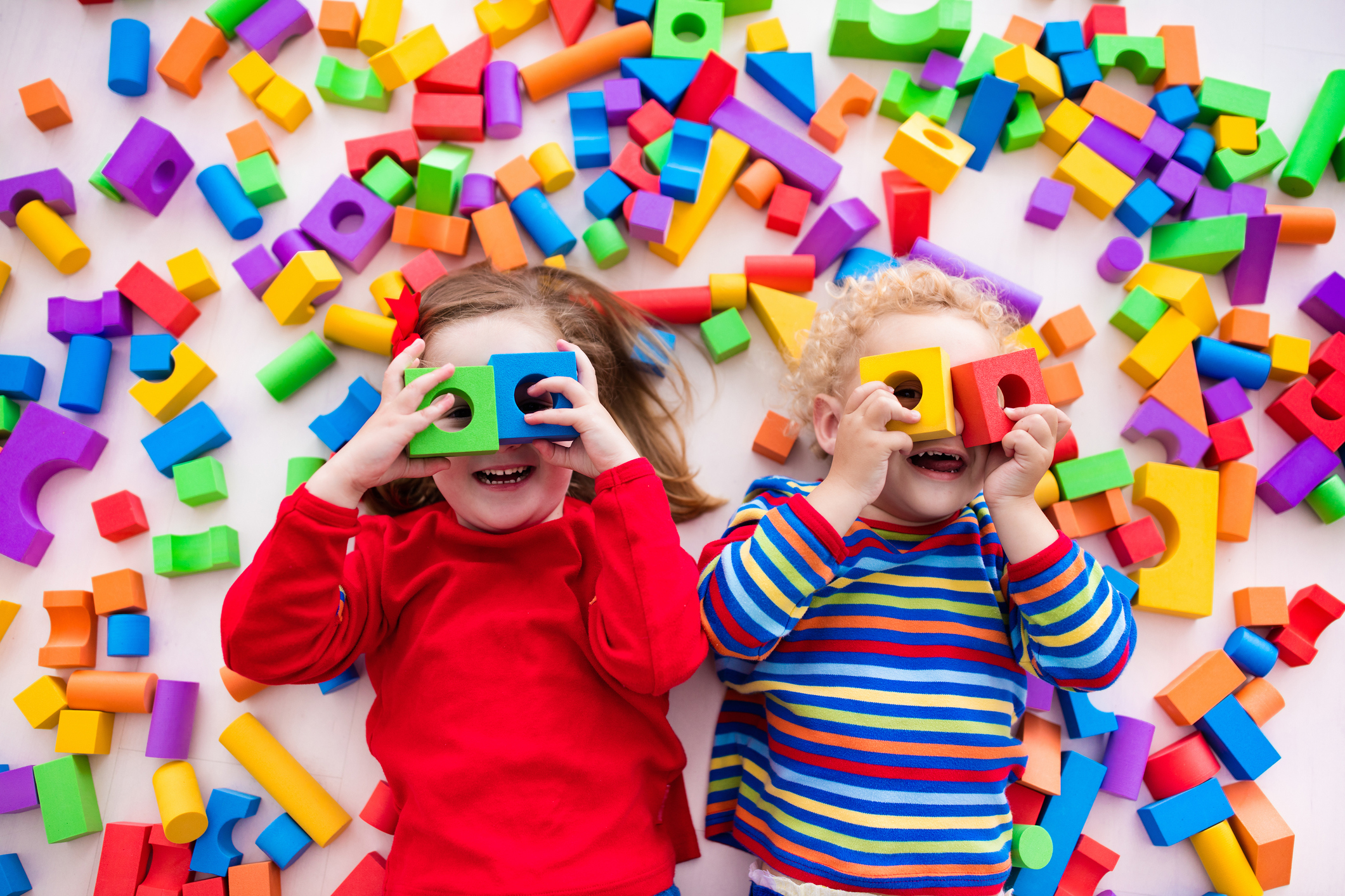 Duas crianças felizes brincam com blocos coloridos de construir brinquedos.